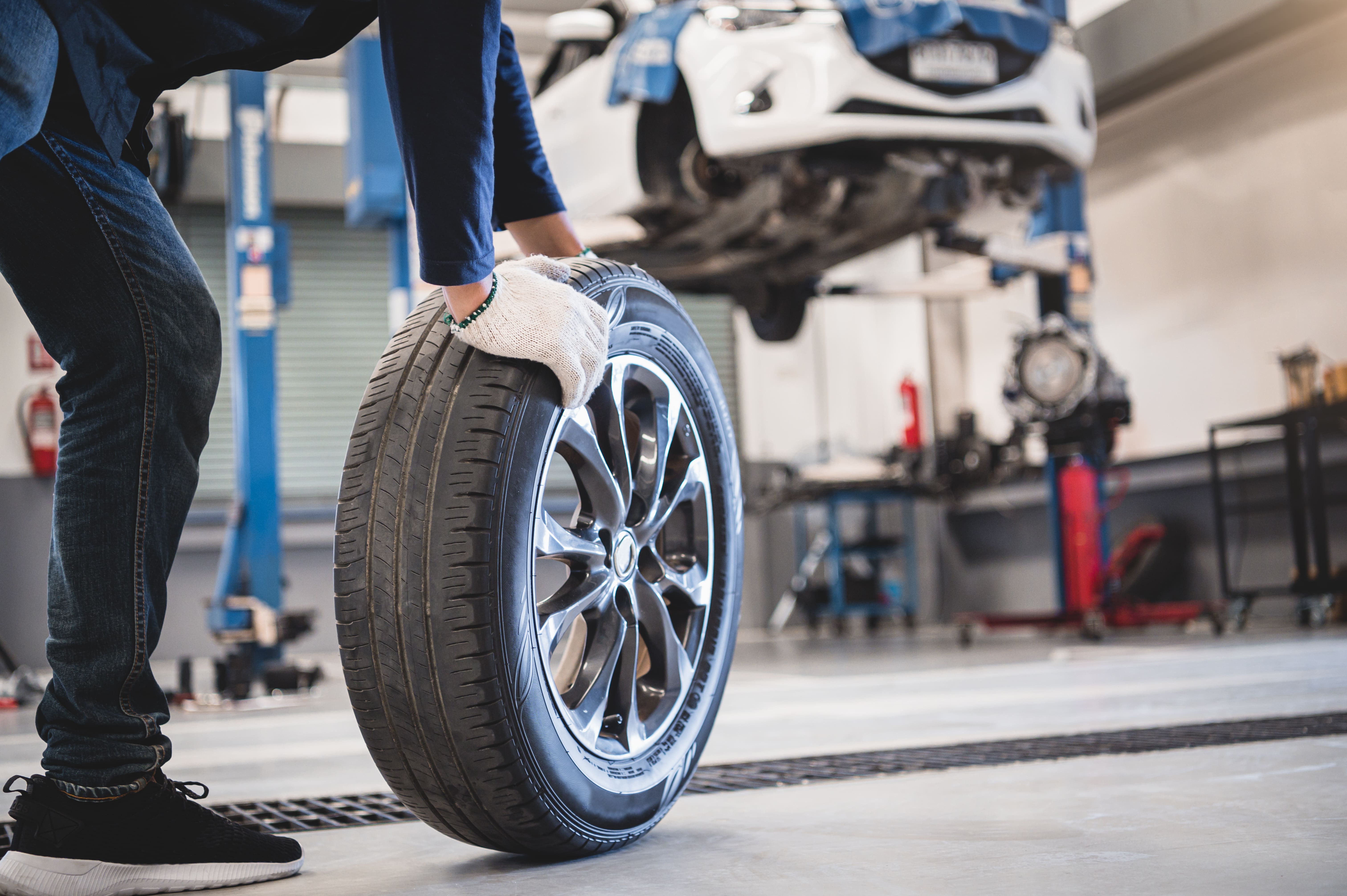 vecteezy_male-mechanic-rolling-tire_1226506